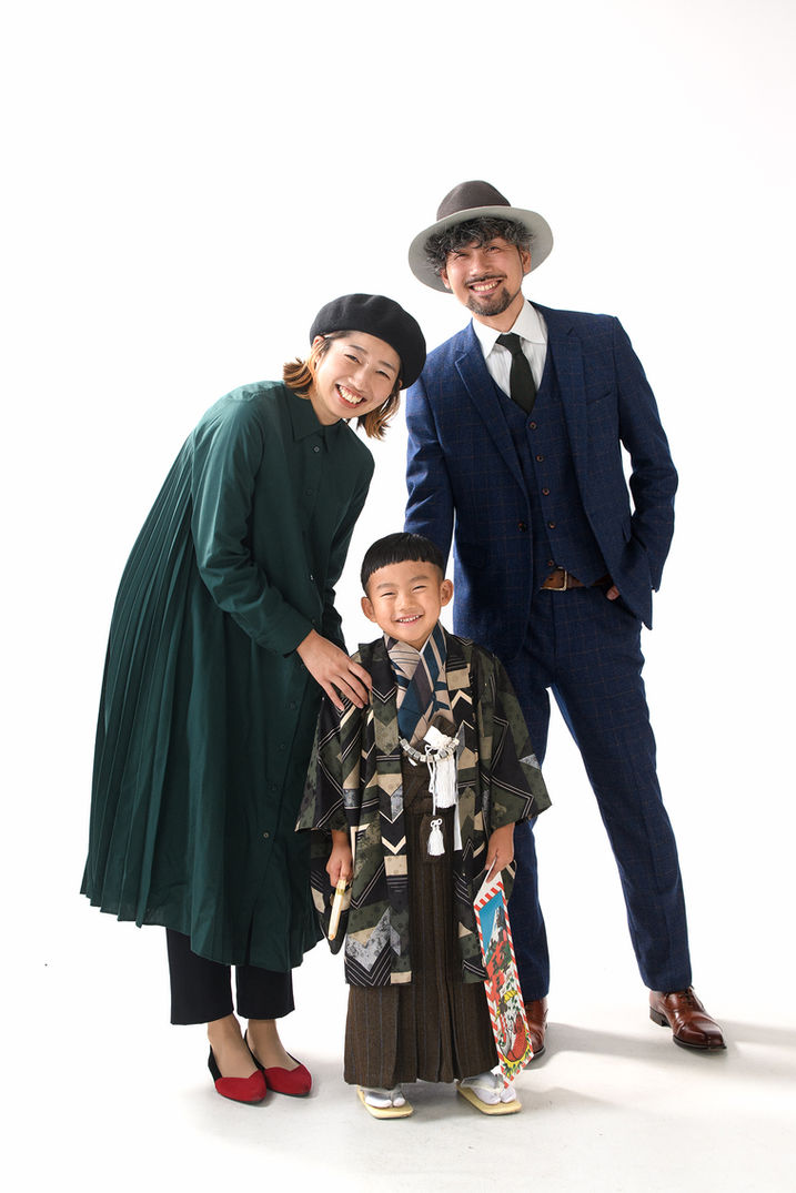 七五三の袴を着て千歳飴を持つ男の子と笑顔の両親