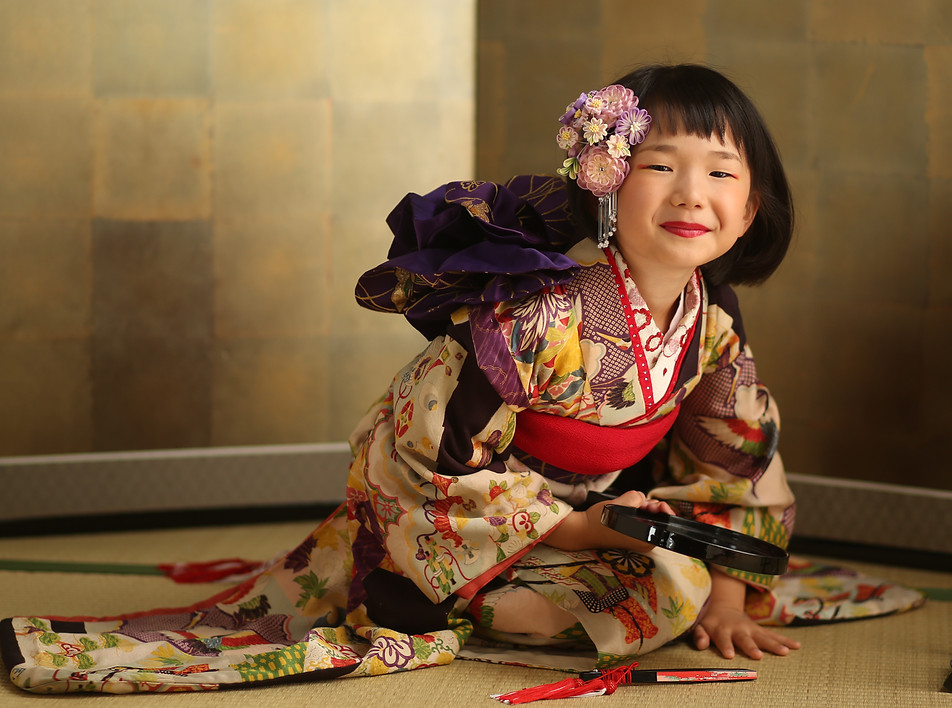 金屏風の前で着物を着て微笑む七五三の女の子
