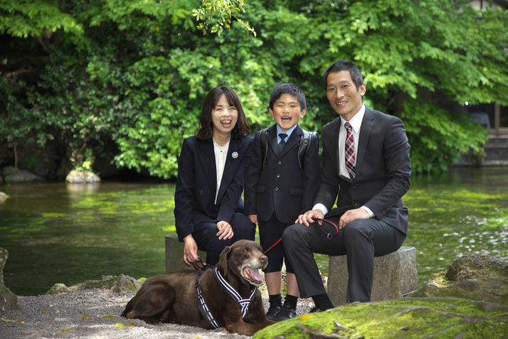 フォーマルな服装の家族と愛犬である大型犬の記念写真