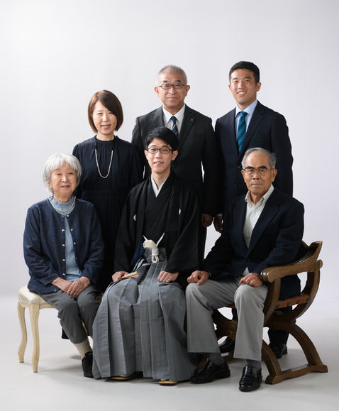 成人式の記念撮影をする紋付羽織袴の男性と家族