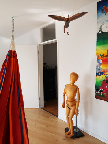 Geräumiger Behandlungsraum mit Hängematte und therapeutischem Spielzeug, freundlich eingerichtet mit Holzboden.