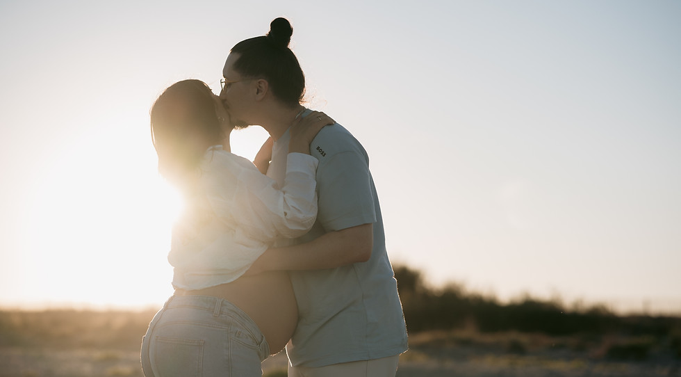 Photo de couple sur la plage au coucher de soleil pour fêter la grossesse et le futur bébé