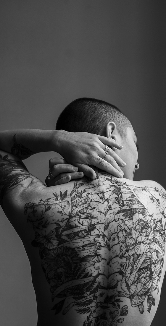 Portrait intimiste d'une jeune femme de dos avec des tatouages intégralement