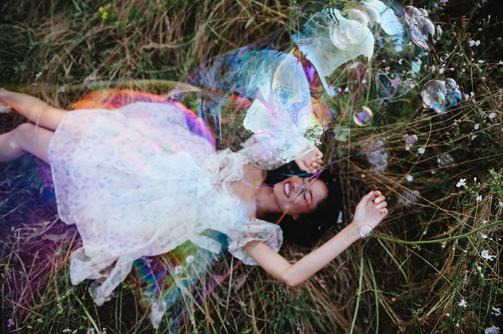 Portrait joyeux et spontané avec bulle de savon géante nette, flou d'arrière-plan végétal.