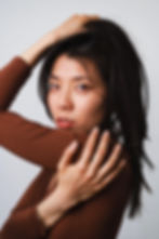 Portrait professionnel d'une jeune femme asiatique en studio photo à Lyon devant un fond blanc qui pose pour l'objectif de Julia Guérin