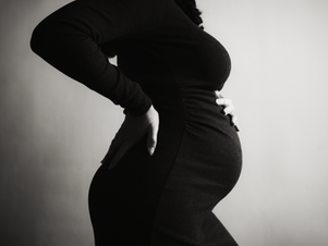 Corps de profil d'une femme enceinte pendant un shooting photo portrait grossesse en noir et blanc à Lyon