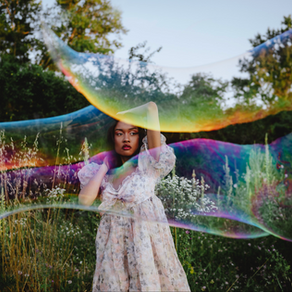 Portrait artistique femme derrière une bulle de savon géante aux reflets iridescents, Parc de la Feyssine Lyon.