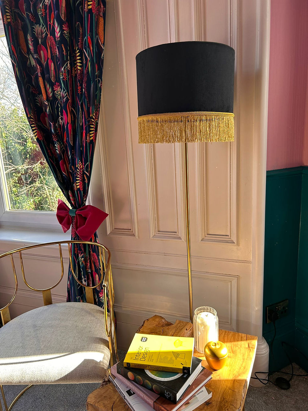 Thumbnail: Black floor lamp with gold fringe, gold chair, and side table