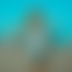 A young woman sits on the back of her boyfriend as they laugh together at their hotel in the sun.