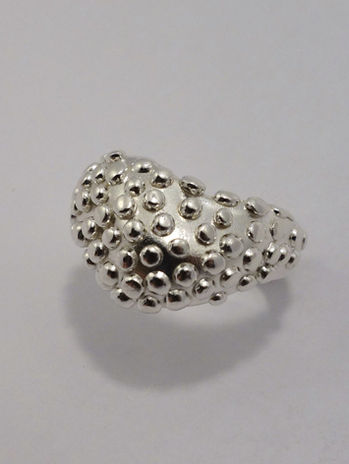 A chunky silver ring with a dotted texture on the upper half, shown from various angles against a light background.