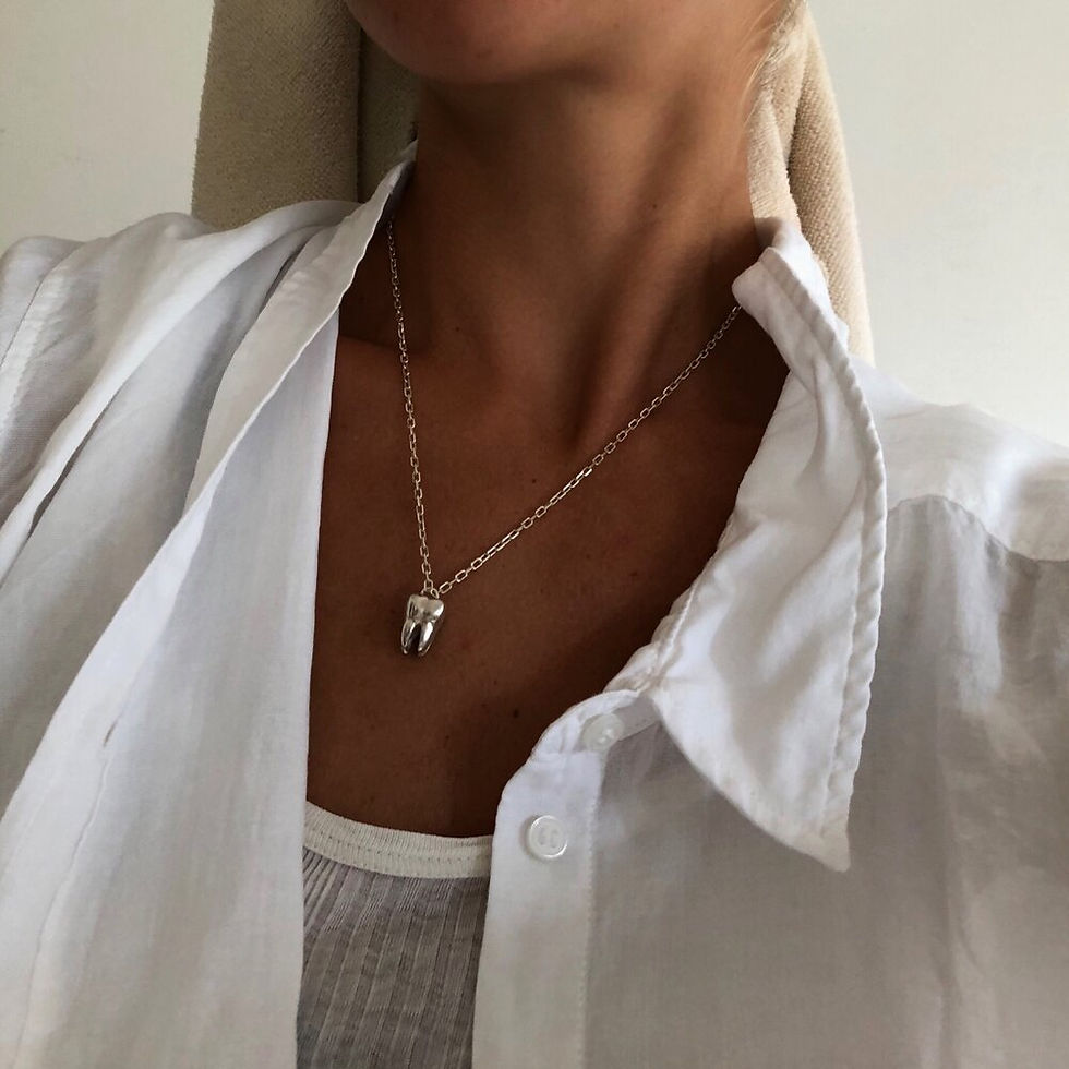 Thumbnail: Close-up of a tooth-shaped pendant necklace worn around the neck