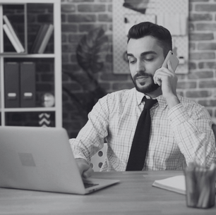 Business man sitting at desk working on the computer whilst on the phone
