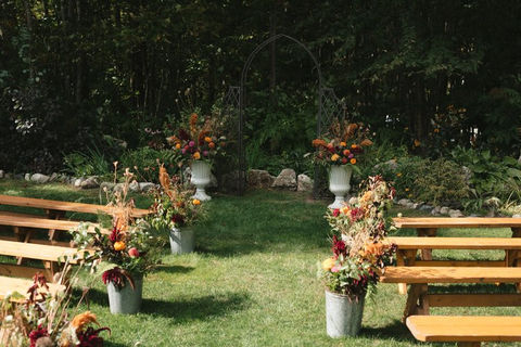 Fall garden wedding ceremony with aisle flowers in red and orange tones