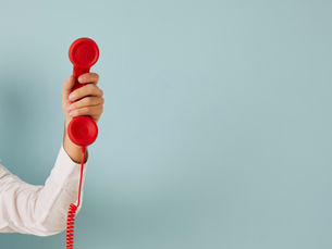 blue back ground, white hand holding a read phone.
