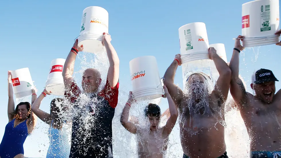 A group of people standing in a line dump ice cold water on their heads