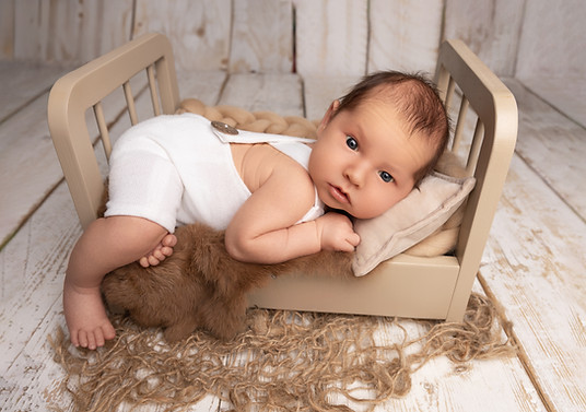 Sleeping newborn posed in rustic basket with neutral tones in Norbury studio