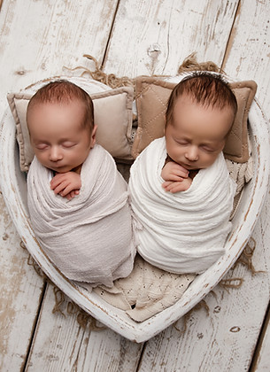 Sleeping newborn twins wrapped in soft neutral tones during studio portrait session