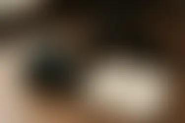 木質桌面上有一台單眼相機與幾顆鏡頭，另外有一本上面記載攝影知識的筆記本