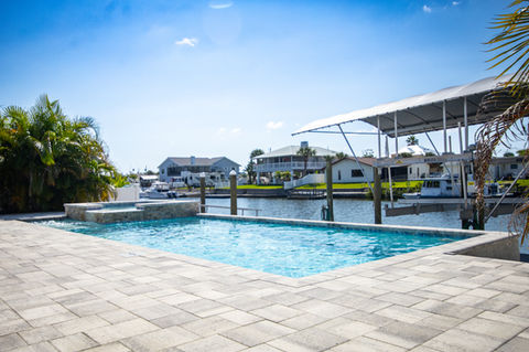 Luxury swimming pool with waterfront view of boat docks and beautiful homes.