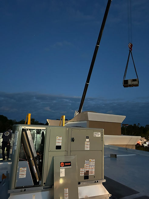 Crane lifting HVAC unit onto rooftop
