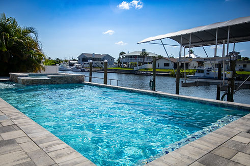 Swimming pool overlooking canal with nearby homes built by Trinity Pools