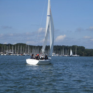 Mirage with sailors on board sailing in the sunshine near Woolverstone marina