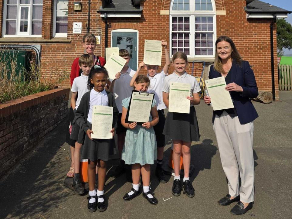 Jenny with students at Bucklesham Primary School holding the petition.
