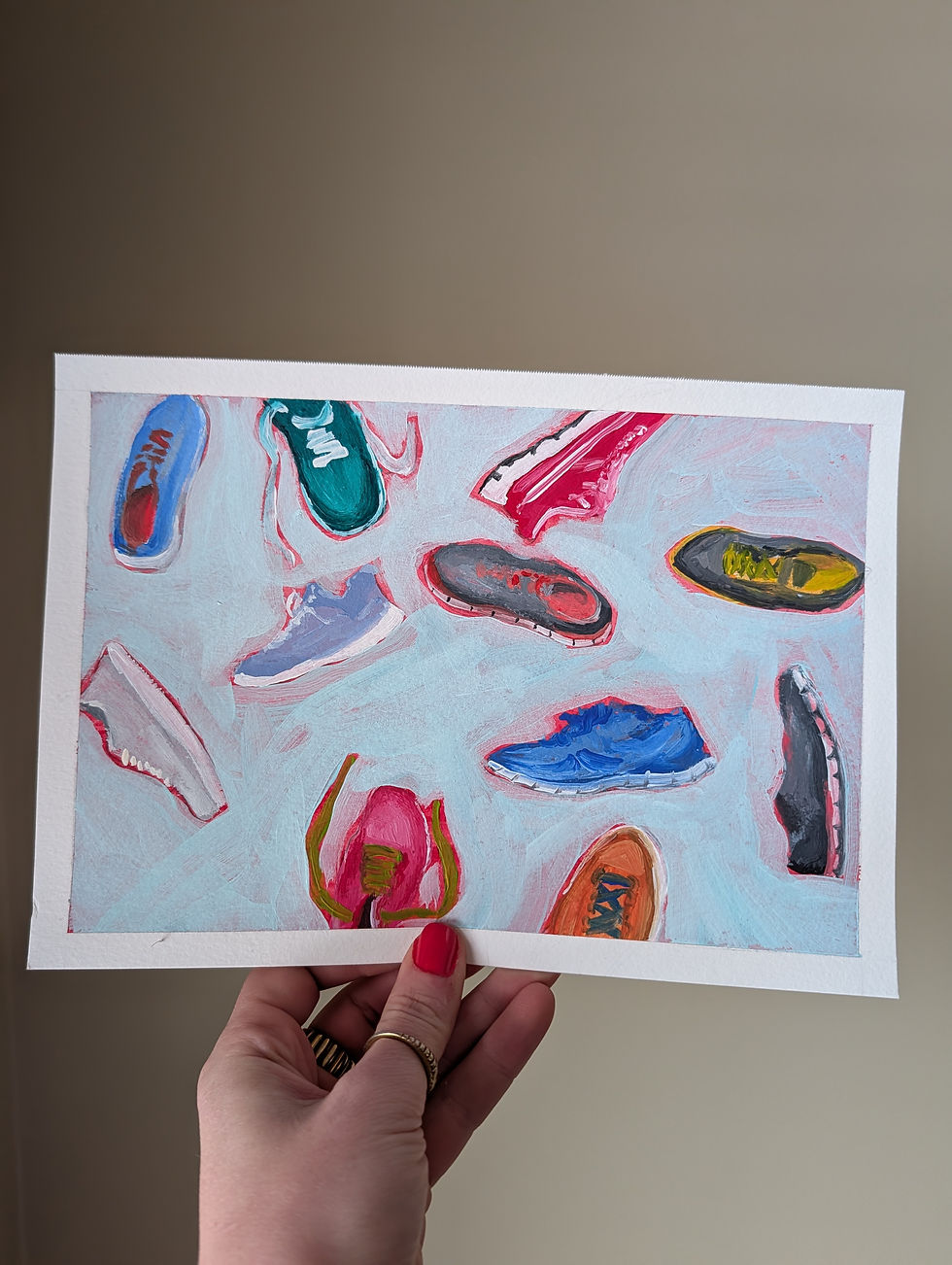 Thumbnail: Painting of running shoes on the ground, some right side up, some on their sides. Painting is being held up by a hand.