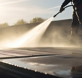 Worker pressure washing a roof