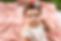 a baby is sitting and smirking on a pink blanket