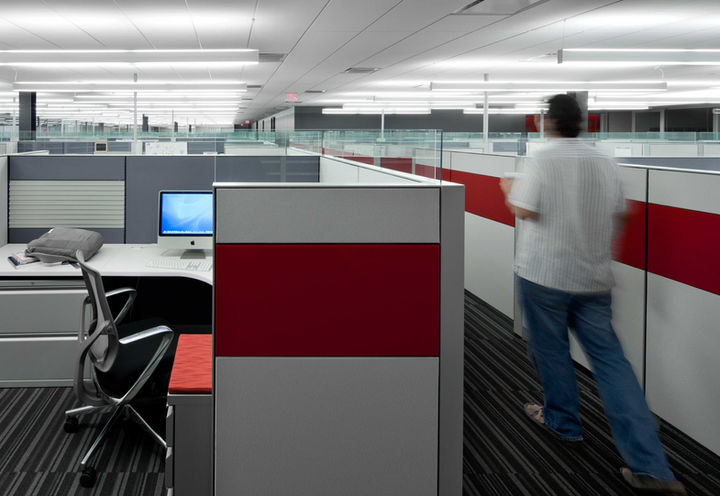 A man walks through a brightly lit open office space accented with red workstation panels at Blackboard Transact's headquarters in Phoenix, Arizona.