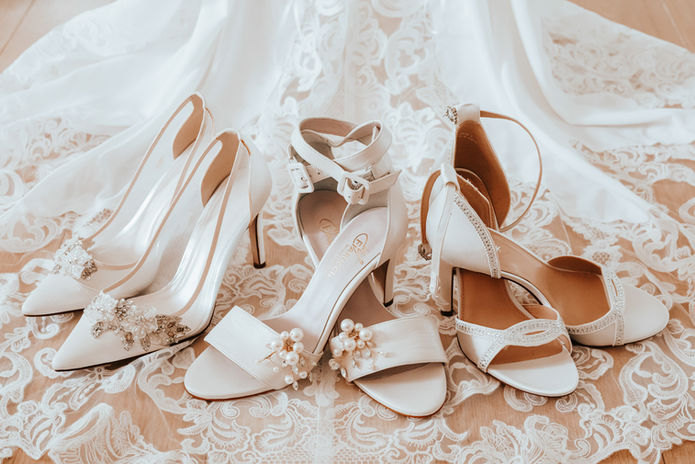 Collection of bridal shoes arranged on lace fabric before a Cyprus wedding ceremony.