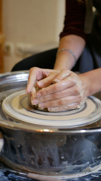 Close-up of a girl's hands shaping clay on a pottery wheel during an art therapy session.