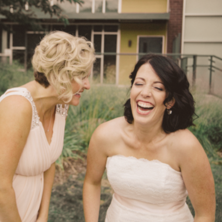 Bride with natural makeup laughing with bridesmaid in garden setting – Seattle wedding makeup artist