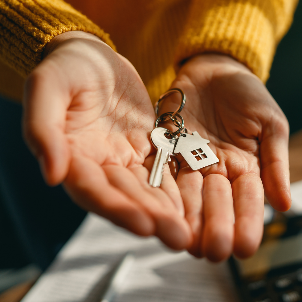 Person holding house key with home-shaped keychain symbolizing buying a home in Woodland Park Colorado