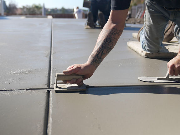 a man smoothes the edge of a concrete patio