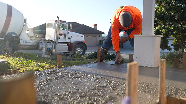 A man smoothes freshly poured concrete walkway