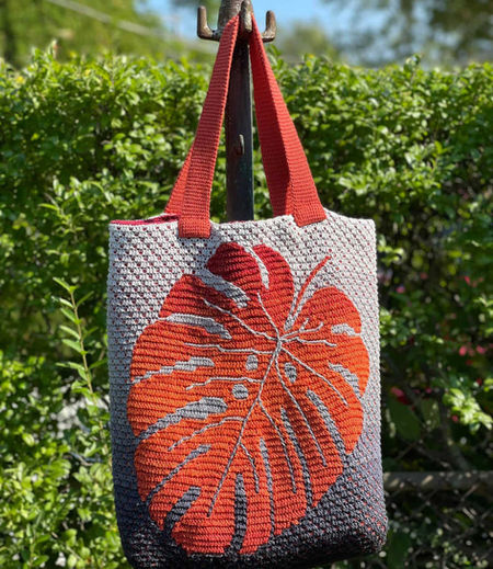 Monstera Bag mosaic crochet pattern with a big monstera leaf on the front side, rectangular bottom, and 2 handles long enough to place the bag over shoulder.