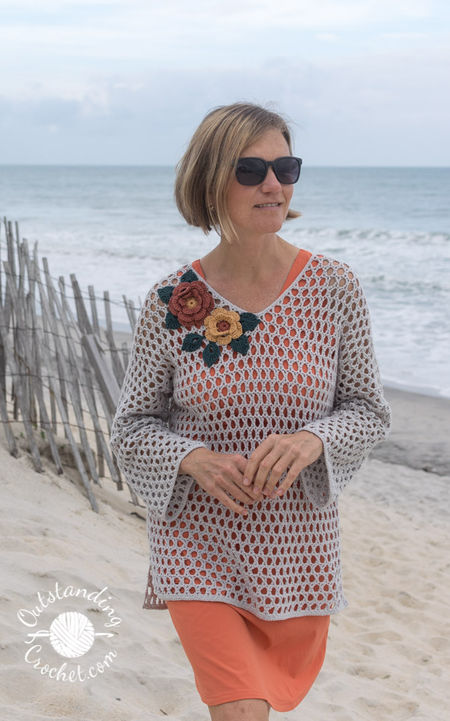 Floral Net Tunic crochet pattern in open mesh stitch with long sleeves and V-neck, with optional flower embellishment.