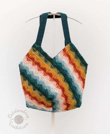 Handmade slouchy crochet shoulder bag featuring vibrant diagonal stripes in a multi-colored spike stitch pattern. The bag is shown in a relaxed, stylish drape, highlighting its large capacity.