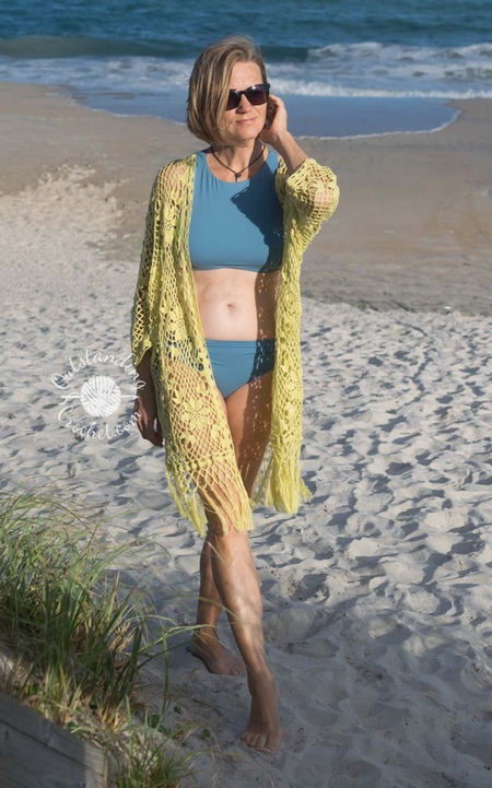 Garden Bohemia women summer lace robe cardigan crochet pattern in floral lace stitch, with long sleeves, an open front, and knotted fringe edging at the bottom. 