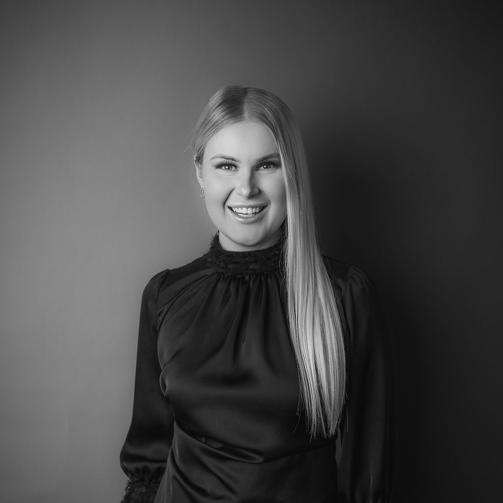 A woman wearing black smiling with her arms folded