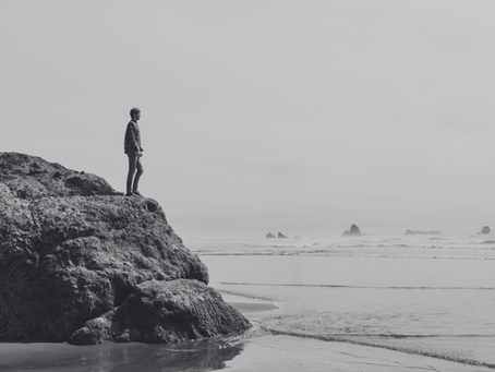 Man standing on rocks looking out into the ocean