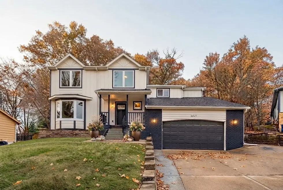 Front exterior of a spacious, upscale 2-story home with attached garage, green lawn, and trees in front.
