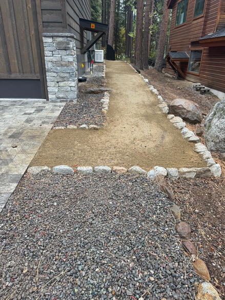 Pathway with gravel, landscaping, and stones outside of a wooden house