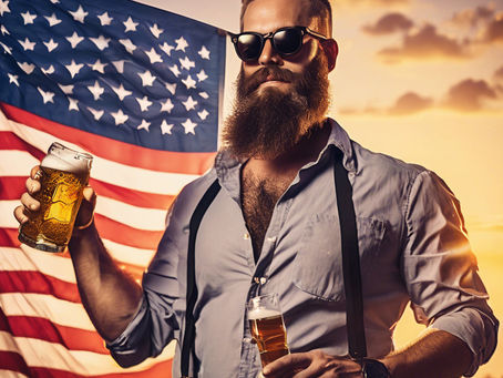 Bearded man with sunglasses holds beer in front of a U.S. flag at sunset, wearing a shirt and suspenders. Relaxed, patriotic mood.