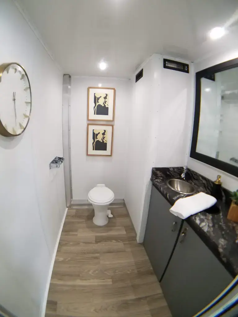 interior of a luxury restroom trailer with flushing toilet and sink.