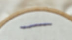 Coral stitch created in purple thread on white fabric