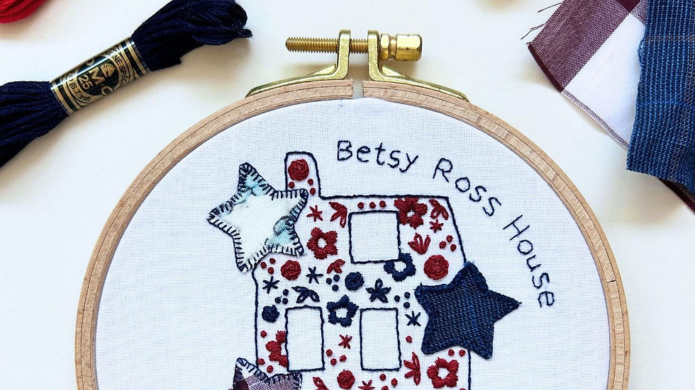 Embroidery hoop featuring a singer sewing machine stitching a colorful patchwork quilt.