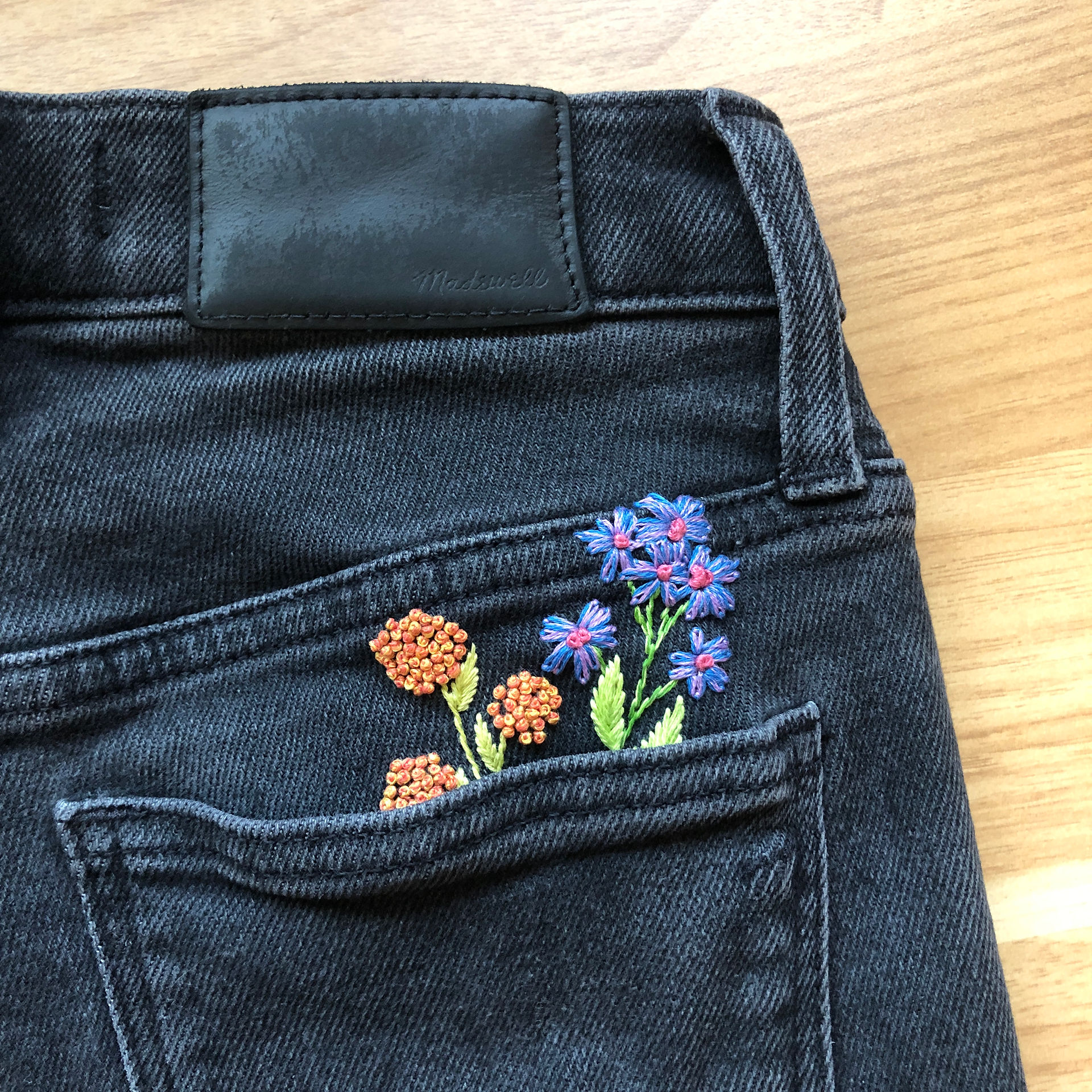 black jeans back pocket with embroidered flowers coming out of the pocket